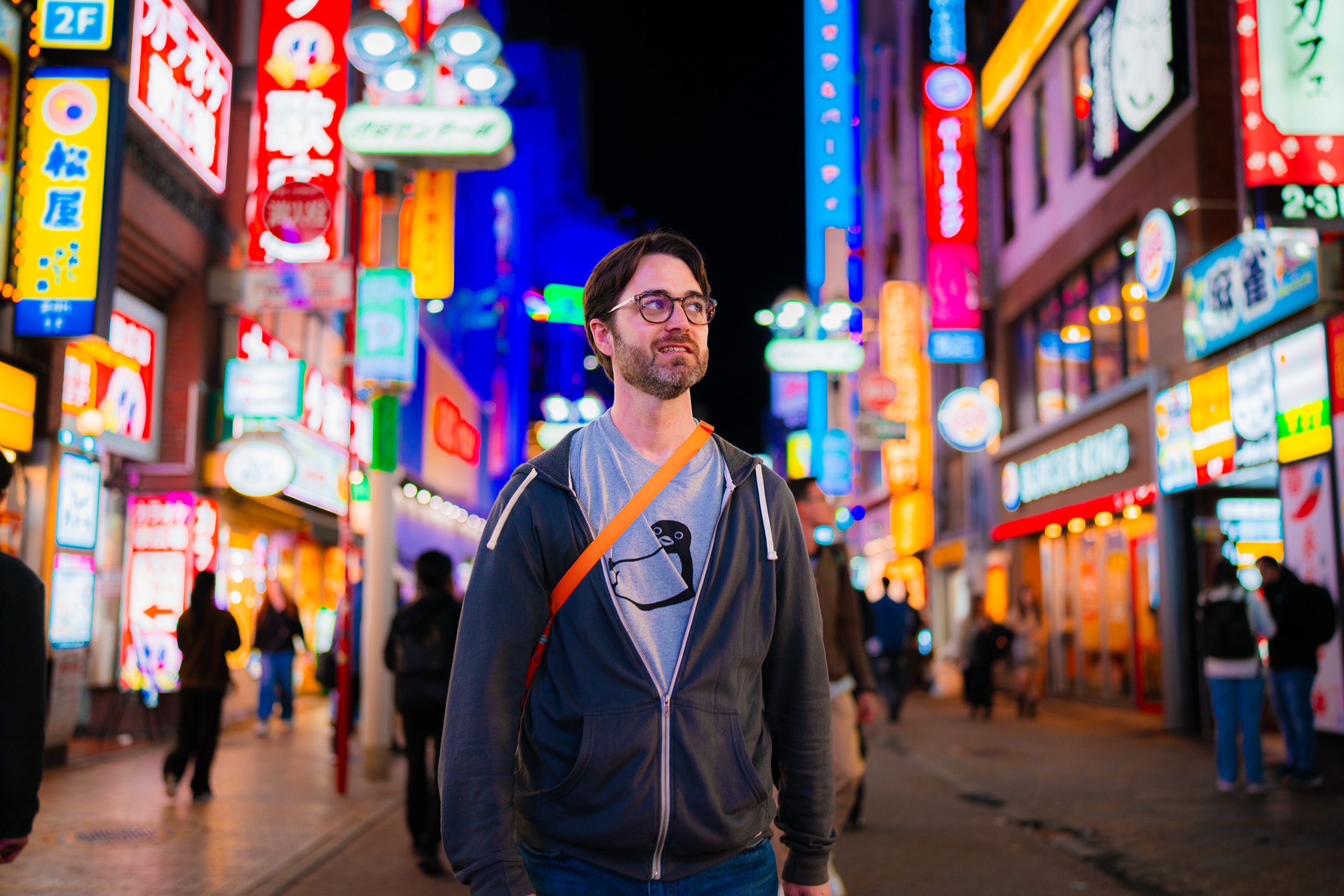 Aydrian standing on a neon-lit Tokyo street at night.